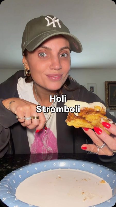 Video still of a customer in a Holi Stromboli branded clip holding a pumpkin bun and smiling