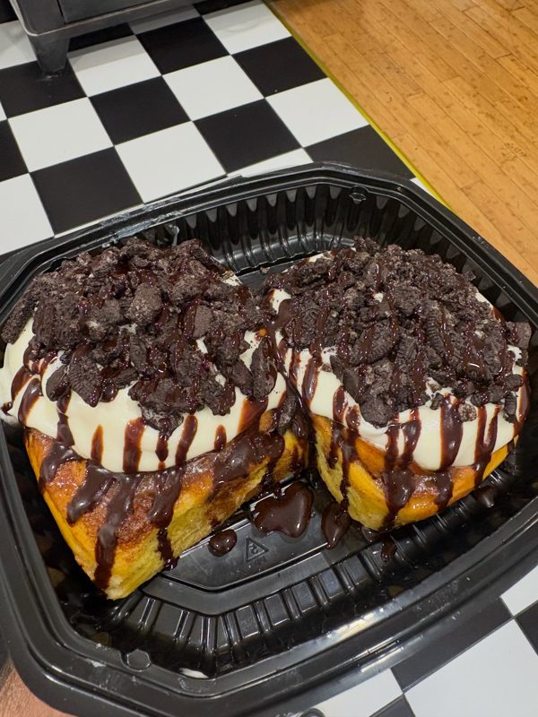 Pumpkin bun halves topped with cream cheese icing, Oreo crumble, and chocolate drizzle